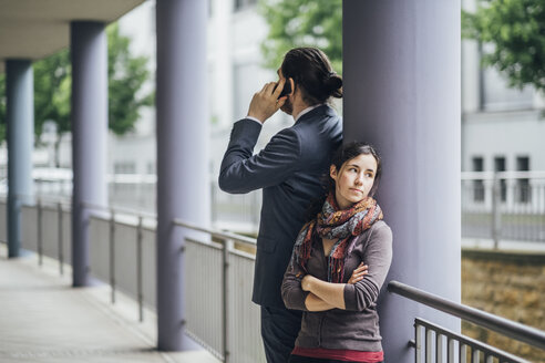 Businessman talking on cell phone with woman looking away - JSCF00063