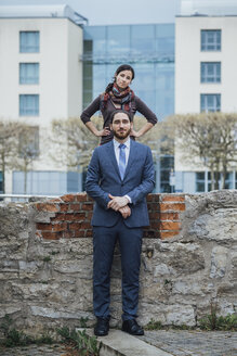 Portrait of businessman and woman at a wall outside office building - JSCF00065