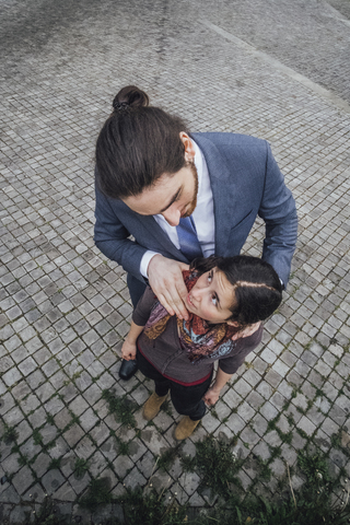 Businessman standing on cobblestones looking at woman with hand on her shoulders stock photo