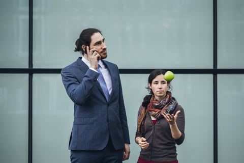 Businessman talking on cell phone and woman throwing an apple stock photo