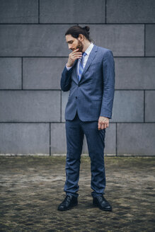 Serious businessman standing outdoors looking down - JSCF00086