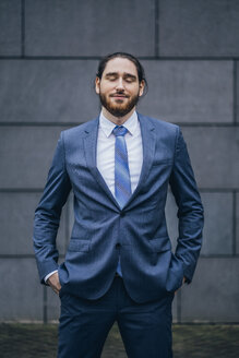 Portrait of smiling businessman standing outdoors with closed eyes - JSCF00088