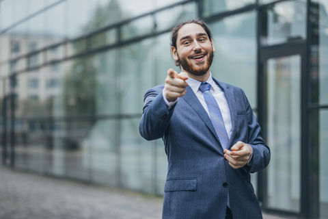 Porträt eines glücklichen Geschäftsmannes, der im Freien steht und mit dem Finger zeigt, lizenzfreies Stockfoto