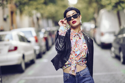 Portrait of fashionable young woman wearing sunglasses and leather jacket - JSMF00123