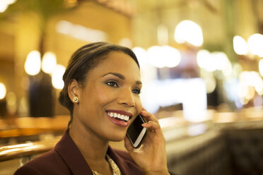 Geschäftsfrau, die in einem Restaurant mit ihrem Handy telefoniert - CAIF16304