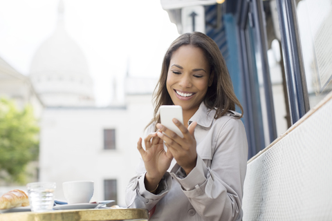 Geschäftsfrau benutzt Mobiltelefon in einem Straßencafé, lizenzfreies Stockfoto