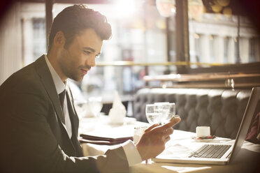 Businessman using laptop in restaurant - CAIF16322