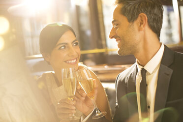 Well-dressed couple toasting champagne flutes in restaurant - CAIF16346