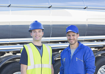 Portrait of confident workers next to stainless steel milk tanker - CAIF16367