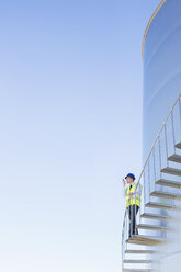 Arbeiter mit Walkie-Talkie auf der Wendeltreppe am Silageturm - CAIF16372