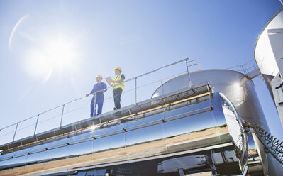 Workers on platform above stainless steel milk tanker - CAIF16376