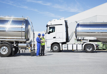 Arbeiter im Gespräch neben Milchtankwagen aus Edelstahl - CAIF16389