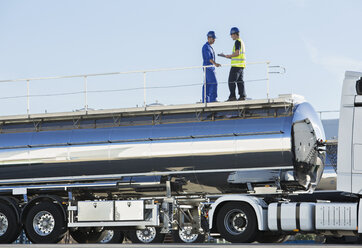 Arbeiter auf einer Plattform über einem Milchtankwagen aus Edelstahl - CAIF16398