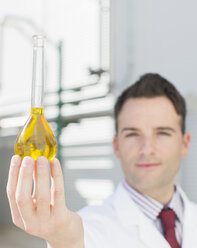 Portrait of scientist holding beaker with liquid - CAIF16404