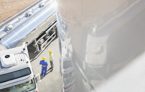 Arbeiter unterhalten sich neben einem Milchtankwagen aus rostfreiem Stahl, lizenzfreies Stockfoto