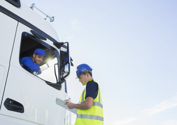 Arbeiter mit Klemmbrett im Gespräch mit Lkw-Fahrer - CAIF16409