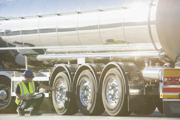 Worker checking tire on stainless steel milk tanker - CAIF16418