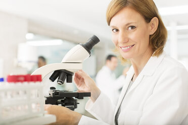 Portrait of confident scientist using microscope in laboratory - CAIF16495