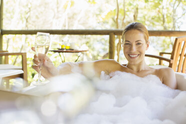 Woman drinking champagne in bubble bath - CAIF16574