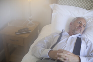 Businessman relaxing on bed in hotel room - CAIF16600