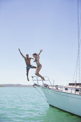 Couple jumping off boat into water - CAIF16628