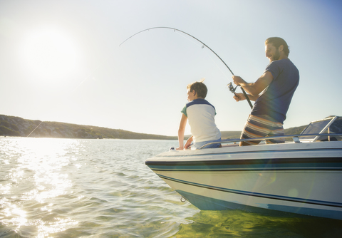 Vater und Sohn fischen auf einem Boot, lizenzfreies Stockfoto