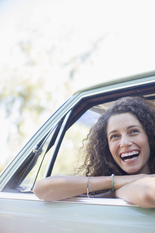Frau entspannt sich während einer Autofahrt auf der Autotür, lizenzfreies Stockfoto
