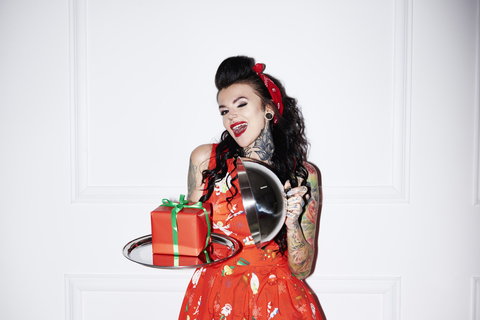 Portrait of tattooed woman presenting present on silver platter stock photo