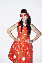 Portrait of tattooed woman wearing patterned red dress - ABIF00135