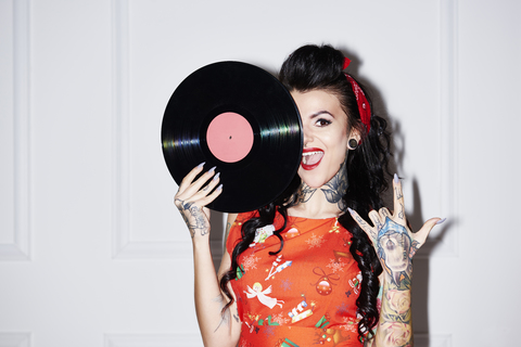 Portrait of tattooed woman with record showing Rock And Roll Sign stock photo