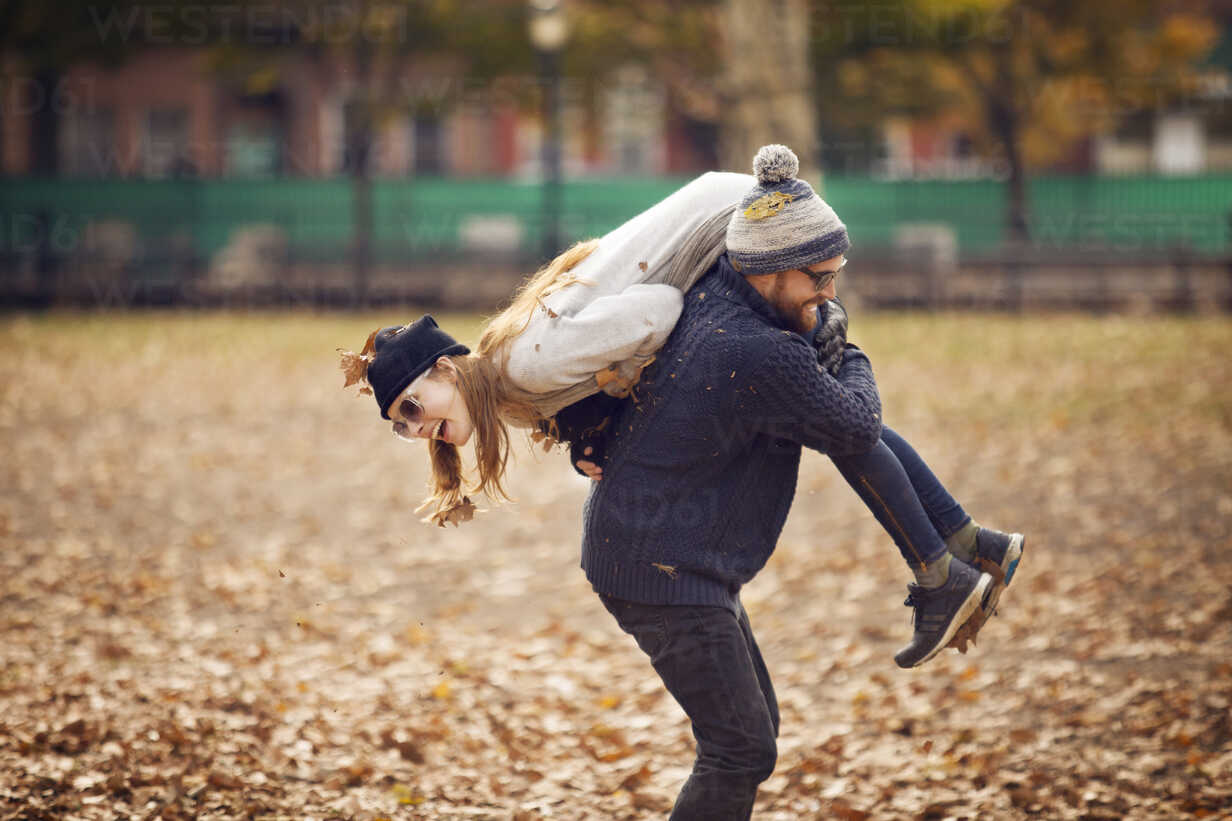 Mann trägt Frau auf der Schulter, während er im Park steht ...