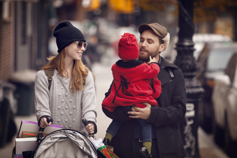 Vater trägt seine Tochter, während er mit seiner Frau auf der Straße spazieren geht, lizenzfreies Stockfoto