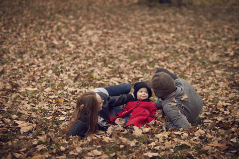 Eltern mit Baby entspannen sich auf einer Wiese im Park, lizenzfreies Stockfoto
