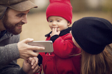 Vater zeigt seinem Baby im Park das Smartphone - CAVF08379