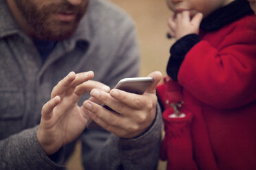 Mittelteil eines Vaters mit einem kleinen Mädchen bei der Benutzung eines Smartphones im Park - CAVF08380