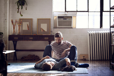 Man looking at boyfriend lying on floor at home - CAVF08397