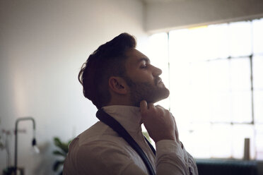 Side view of man tying necktie - CAVF08419