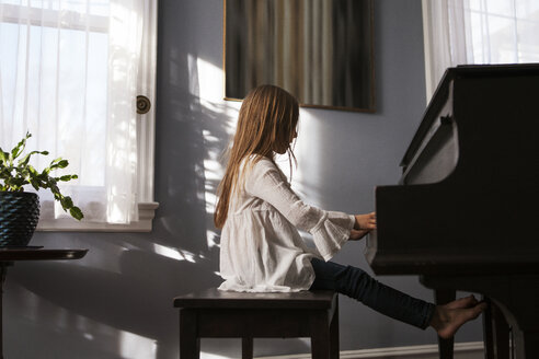 Seitenansicht eines Mädchens, das zu Hause Klavier spielt - CAVF08484