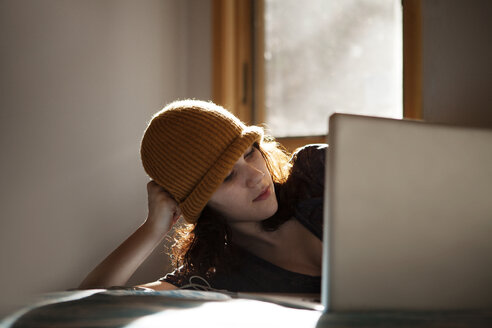 Teenager-Mädchen benutzt einen Laptop, während sie zu Hause auf dem Bett liegt - CAVF08532