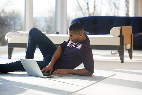 Mann arbeitet zu Hause sitzend am Laptop - CAVF08540