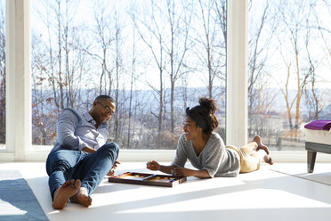 Couple smiling while playing backgammon at home - CAVF08556