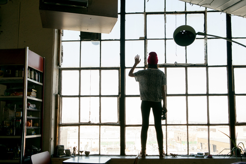 Rear view of woman standing by window at home stock photo