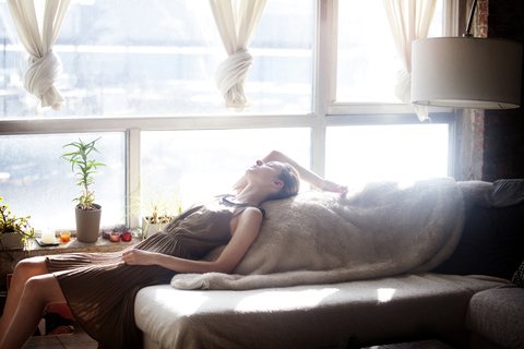Seitenansicht einer Frau, die sich auf dem Sofa entspannt, lizenzfreies Stockfoto