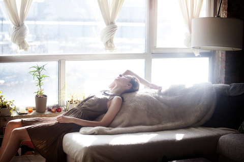 Side view of woman relaxing on sofa stock photo