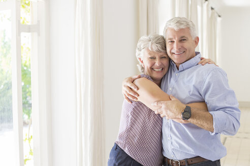 Älteres Paar, das sich im Wohnraum umarmt - CAIF16798