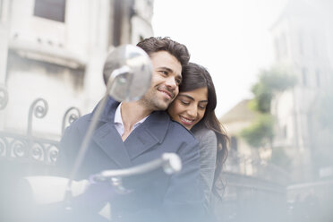 Couple sitting on scooter in city - CAIF16901