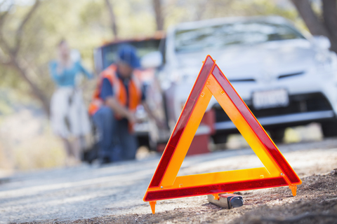 Warndreieck auf der Straße mit Mechaniker im Hintergrund, lizenzfreies Stockfoto