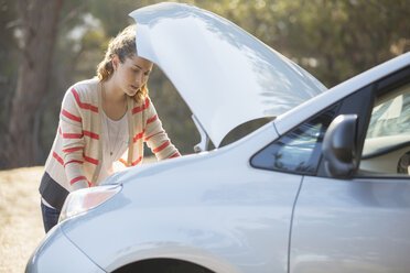 Woman checking car engine at roadside - CAIF16913