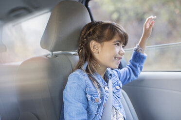 Happy girl sticking hand out car window - CAIF16917