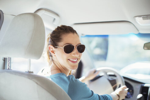 Porträt einer selbstbewussten Frau mit Sonnenbrille am Steuer eines Autos - CAIF16919